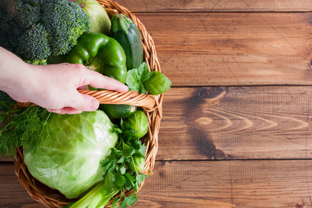 新鲜的绿色蔬菜在一个柳条篮子在木桌上, 复制空间, 顶部视图
