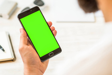 该名男子使用智能手机与绿色屏幕的色度关键复合手拿着黑色智能手机与绿色屏幕色度键合成在线支付塑料卡