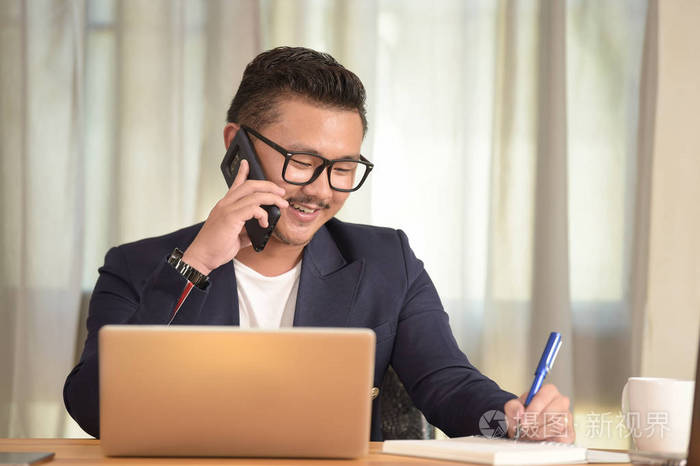 年轻人坐在他办公桌前在办公室里的肖像