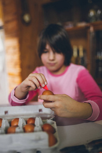 小女孩享受复活节假期。她坐在厨房的桌子上, 画画和装饰鸡蛋。