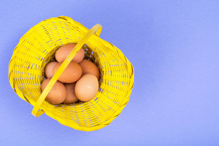 准备复活节。黄色篮子与鸡蛋在紫罗兰色背景