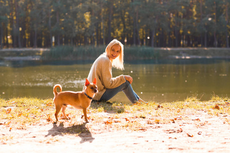 女孩在一个秋天公园在湖附近举行片剂