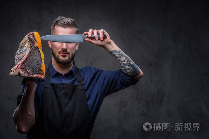 专业屠夫持有刀和大块生肉熏肉