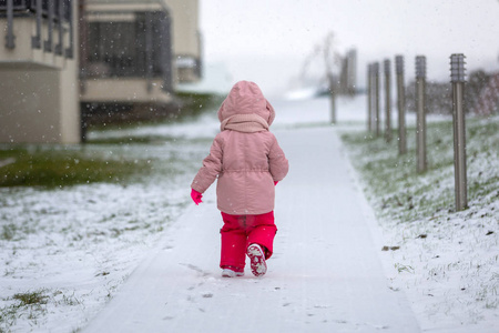 可爱的女孩在冬天夹克奔跑在雪