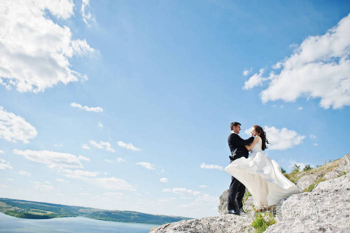 婚礼情侣在惊险的风景与岩石和湖