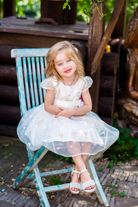 可爱的小宝贝女孩，在美丽的白色礼服，坐在树桩上休闲公园游乐场