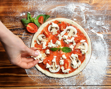 意大利比萨烹调准备过程在质朴的木桌。比萨面团和配料蘑菇香菇