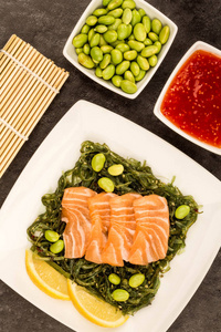 日式鲑鱼刺身在腌海藻沙拉床上图片