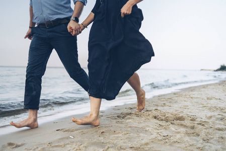 情侣在海边奔跑, 手捧着深蓝色的沙子