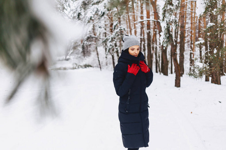 女孩走在白雪覆盖的森林中的松树在红色 g