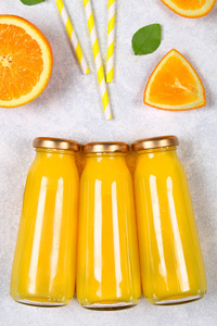 玻璃瓶, 新鲜橙汁橙片和黄色管在一个浅灰色的桌子上。顶部视图。平躺