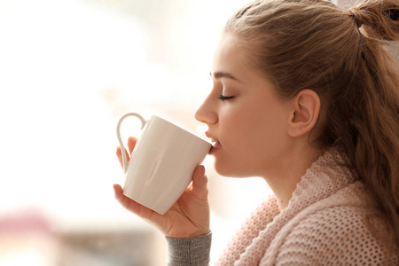 年轻妇女喝茶在模糊的背景