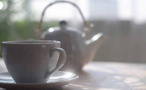 在日光下的桌子上的茶壶的茶白杯