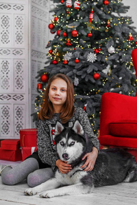 可爱的孩子女孩在圣诞节内部与一只沙哑的狗