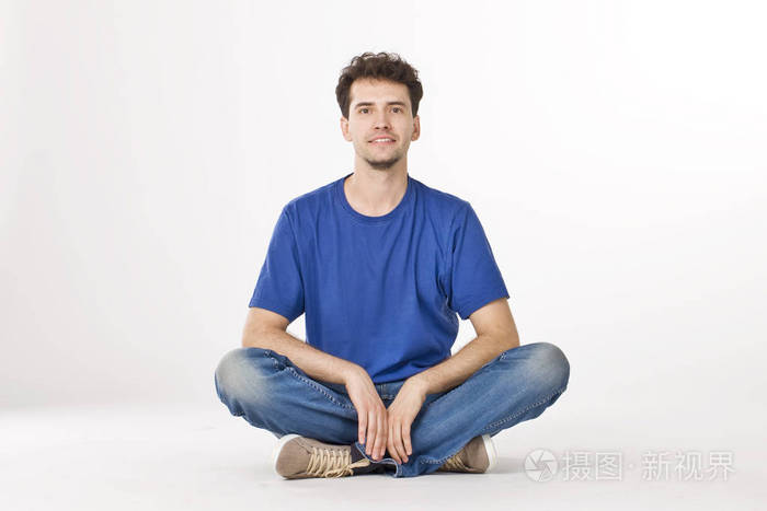 穿着衬衫和牛仔裤的好男孩坐在交叉腿上