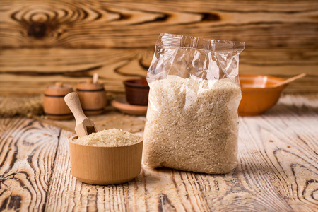 白色大米在包装和碗上的木质背景。健康膳食谷物概念