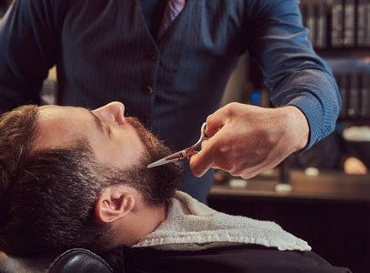 专业理发师建模胡子与剪刀和梳子在理发店。特写照片
