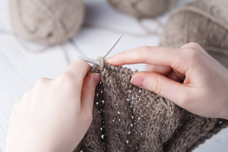 年轻女子 crochets 一条带米色羊毛的暖毯