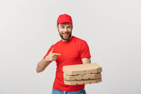 送货理念 英俊的白种人送披萨的男人指着手指。在灰色背景下隔离