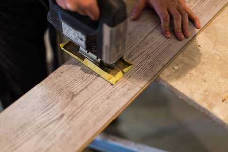 用电锯切割工人强化木地板照片