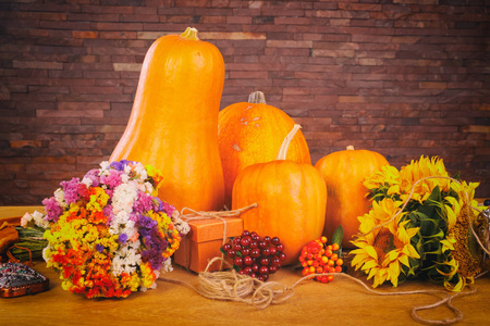 秋天背景用南瓜和花在木桌上。感恩节概念