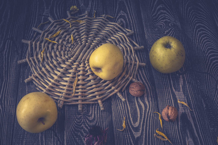 静物苹果和核桃的灰色木质背景。色调图像