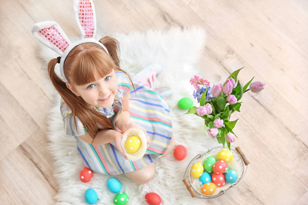 可爱的小女孩与兔子耳朵举行明亮的复活节彩蛋在装饰巢, 室内