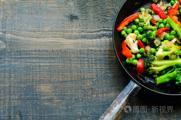 煎蛋和蔬菜混合物煎锅 花生, 花椰菜, 辣椒粉和冰冻的西兰花在天然木质背景, 顶部视图