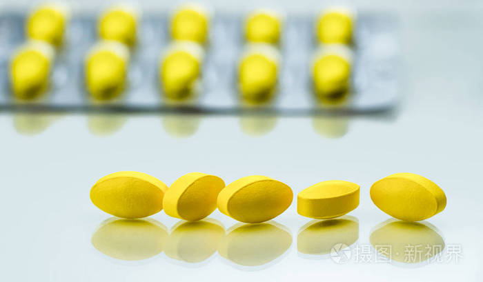 白色背景黄色椭圆形片剂丸的宏观拍摄细节以水泡包装为背景