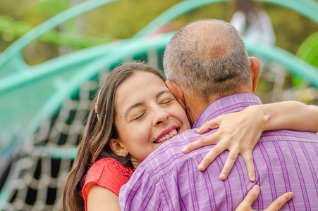女儿在公园的户外拥抱他的父亲与爱的亲密