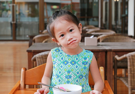 微笑的小亚洲女孩在餐馆吃早餐与看照相机