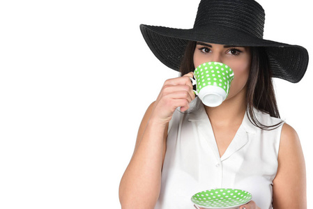 戴黑帽子的年轻女子拿着一杯咖啡或茶。在白色背景上被隔离