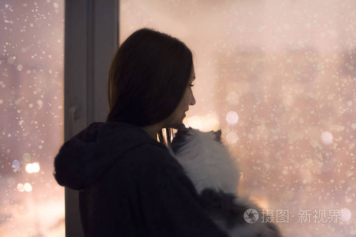 女孩和猫看窗外在雪