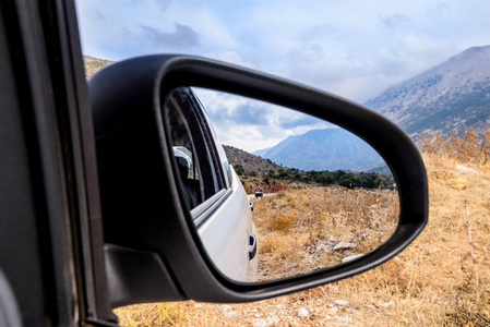 从在希腊, 克里特岛的道路上的汽车窗口的山景景观。镜子里的倒影。旅行乘汽车