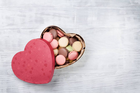 五颜六色的杏仁在情人节的心形礼品盒上木桌上。带空间的顶部视图