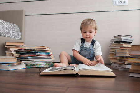 一个小孩子坐在地板上, 坐着一本大书。