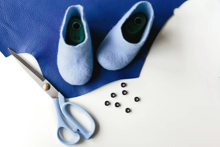 蓝色手工鞋由美利奴羊毛皮革背景制成。下剪刀显示工作过程
