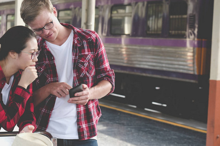 男人和女人在火车站使用智能手机的应用。旅行者