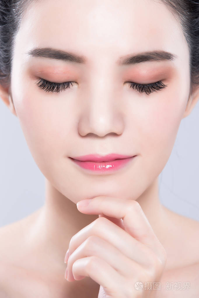 闭着眼睛的女人在灰色背景上抚摸下巴