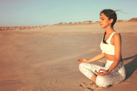 运动的年轻妇女在海滩做瑜伽练习, 健康生活的概念和身体与精神发展之间的自然平衡