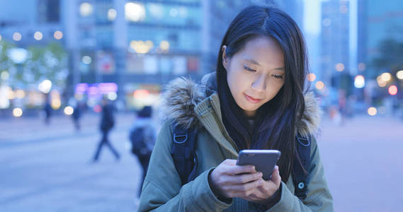 女人晚上在城市中使用手机