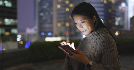 在夜间使用智能手机的女人