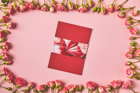 在粉红色的美丽的粉红色玫瑰和贺卡的框架的顶部视图
