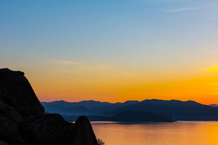 宁静的海湾在黄昏与岩石海岸剪影