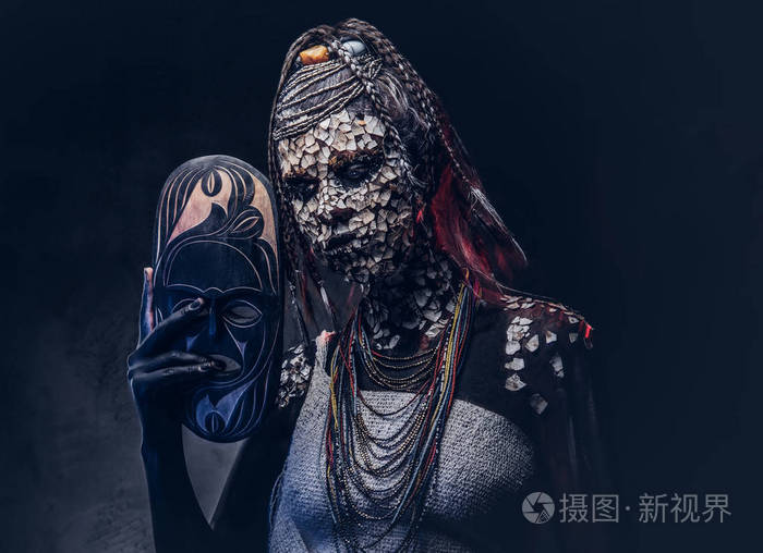 一个可怕的非洲萨满女性的肖像与石化破裂的皮肤和辫子 持有一个传统的面具在黑暗的背景 化妆概念照片 正版商用图片049c3o 摄图新视界 一个可怕的非洲萨满女性的肖像与石化破裂的皮肤和辫子 持有一个传统的面具在黑暗的背景 化妆概念照片 正版商用图片049c3o 摄图新视界