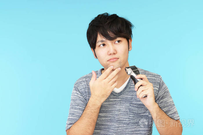 一名男子用电动剃刀剃须
