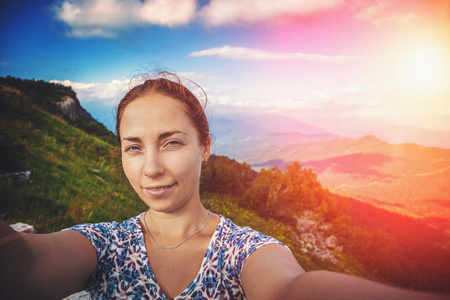 微笑的年轻妇女采取自拍在山背景, 夏天旅行