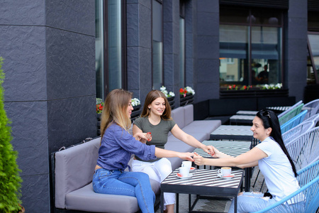 快乐的女性朋友牵手在咖啡馆喝咖啡