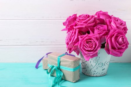 粉红色的玫瑰花在锅和盒与目前的绿松石木背景对白色的墙壁。选择性对焦。文本位置