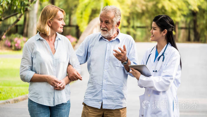 医生与老夫妇谈论医疗咨询在公园.医疗保健理念